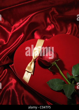 Red heart-shaped gift box and a red rose Stock Photo