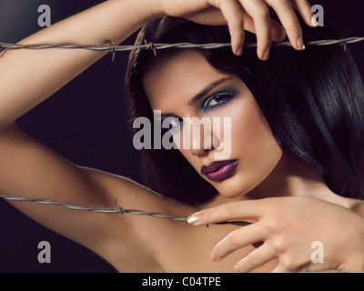 Artistic expressive beauty portrait of a young beautiful woman behind barbed wire Stock Photo
