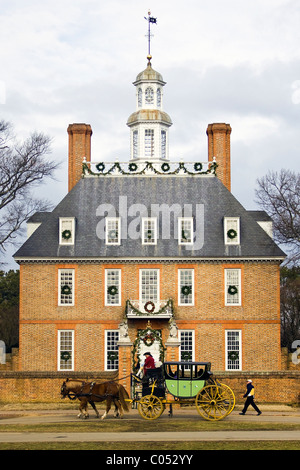 A coachman driving tourists by the Governor's Palace adorned with Christmas decorations in Historic Colonial Williamsburg, VA. Stock Photo