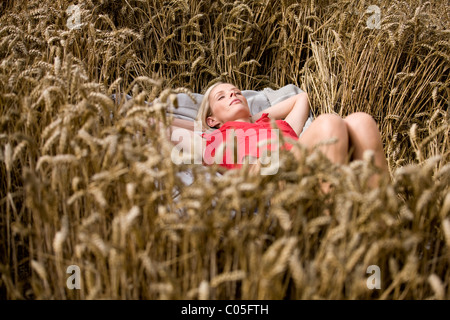 A woman lying in a wheatfield in summertime Stock Photo