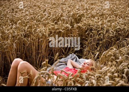 A woman lying in a wheatfield in summertime Stock Photo