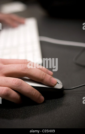 Closeup of a mans hands using a mouse and computer keyboard while gaming or surfing the world wide web. Shallow depth of field. Stock Photo