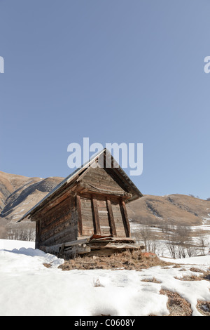 Cottage in winter mountain landscape with blue cloudy sky. Alps. France. Stock Photo