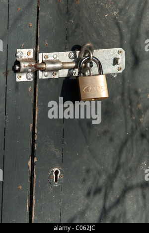A brass padlock on a shed door.  Padlocks are useful to deter casual thieves. Stock Photo