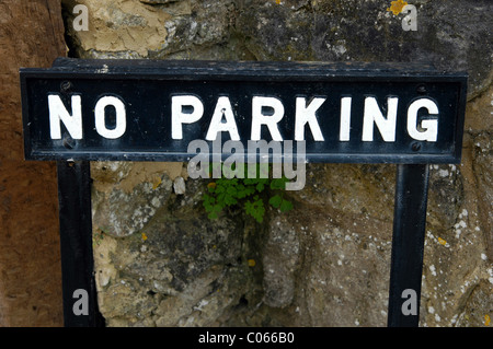 A cast metal 'No Parking' sign in a private road in an English village.  The letters are capitals, and black &white. Stock Photo