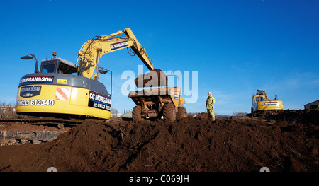 Mechanical diggers excavating earth on a building site in Wales, UK Stock Photo