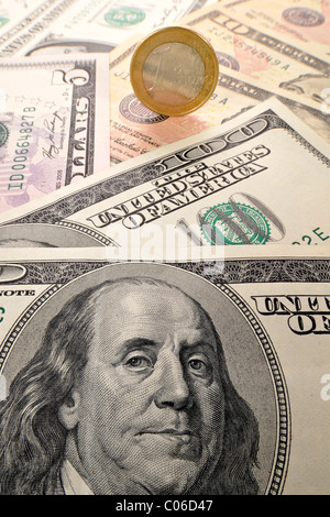 1 euro coin balancing on U.S. dollar banknotes, symbolic image of exchange rates, strong and weak currency Stock Photo