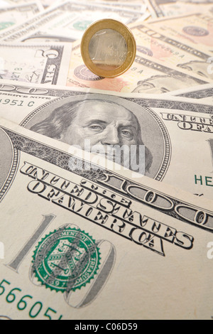 1 euro coin balancing on U.S. dollar banknotes, symbolic image of exchange rates, strong and weak currency Stock Photo