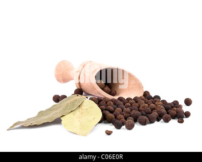 Whole allspice berries, two bay leafs and wooden shovel on white background Stock Photo