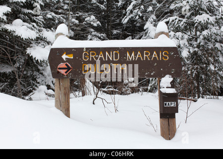 Sign on the Superior Hiking Trail in Northern Minnesota during winter with direction arrows pointing to Grand Marais and Duluth. Stock Photo