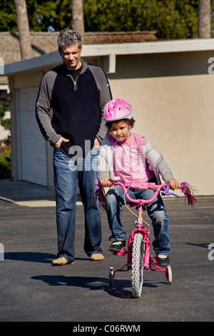 Dad watches his his five year old daughter learn to ride her new bicycle in a safe parking lot in Laguna Niguel, CA. MODEL RELEA Stock Photo