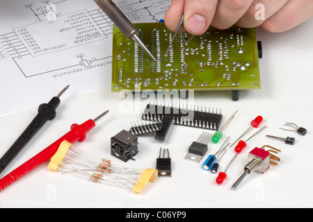 Engineer soldering circuit board surrounded by spare components Stock Photo