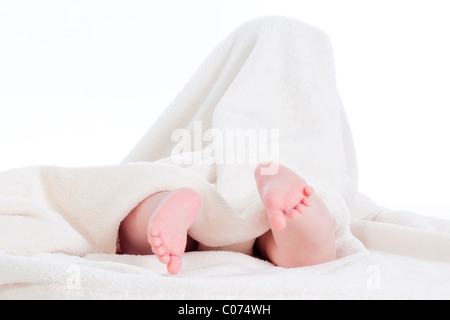 baby wrapped in white towel with its feet sticking out Stock Photo
