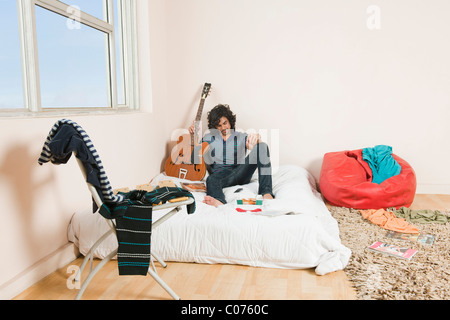 Man holding a guitar in the bedroom Stock Photo