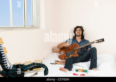 Man playing a guitar in the bedroom Stock Photo