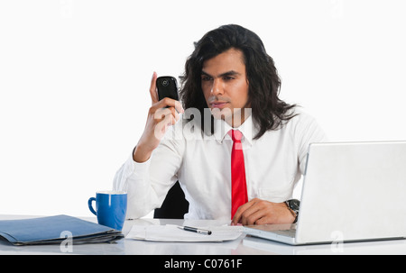 Businessman reading text message on a mobile phone at the desk Stock Photo