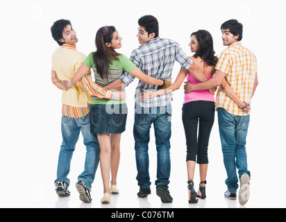 Rear view of college students walking with their arms around each other Stock Photo