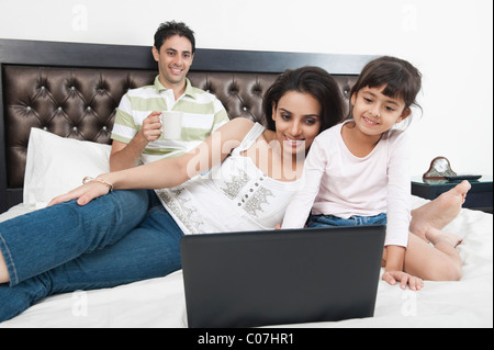 Girl using a laptop with her parents Stock Photo