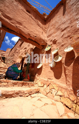 Old woman working in traditional crafts, old Berber adobe-brick village, famous film set, UNESCO World Heritage Site at the foot Stock Photo