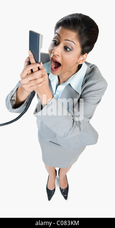 Businesswoman shouting into a telephone receiver Stock Photo
