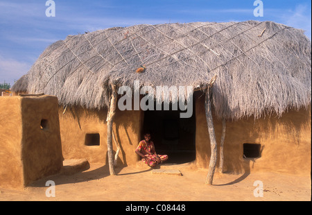 Little girl in front of traditional house, made of cow dung and sand, with thatched roof, Thar Desert, Rajasthan, India, Asia Stock Photo