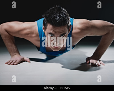 Young caucasian male in sportswear doing push ups on black background. Horizontal shape, front view, copy space Stock Photo