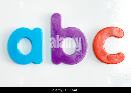 Fridge magnet: colorful plastic alphabet letters on textured white refrigerator. Stock Photo