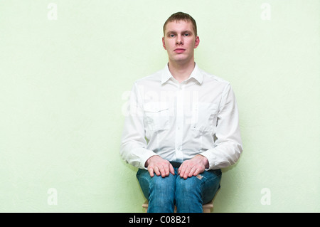 Handsome young man sitting near the wall. Copy space Stock Photo