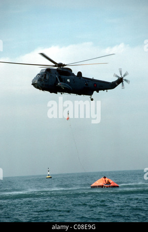 Helicopter coming to the rescue of men in a dinghy at sea Stock Photo