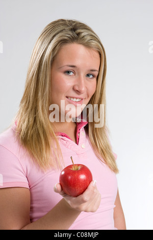 A young woman smiles while holding out a red apple. Stock Photo