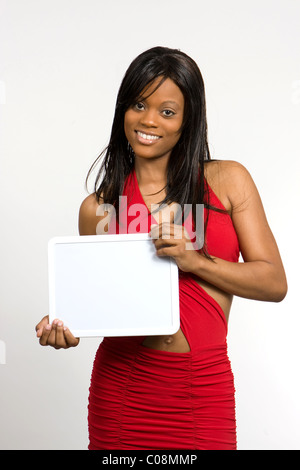 A young and pretty African-American woman with a friendly smile holds a blank slate to be filled with text. Stock Photo