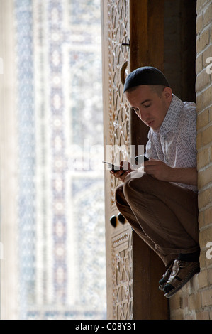 Muslim man at the Kalon Mosque with 2 mobile phones in hand. Bukhara, Uzbekistan Stock Photo