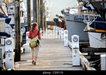 Female tourist tours the harbor in the evening at Thomas Basin, Ketchikan, Southeast Alaska, Summer Stock Photo