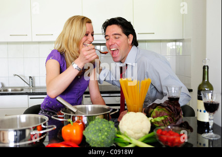 Young couple preparing dinner, she lets him taste Stock Photo