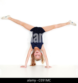 Girl child performing gymnastic balance training on white background Stock Photo