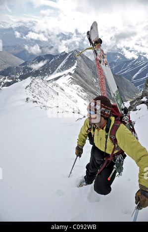 Backpacker looks over the scene below as he climbs the West Ridge of Mt. Chamberlin in the Brooks Range, ANWR, Arctic Alaska Stock Photo