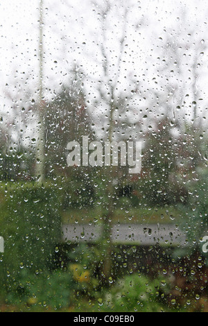 A view out of a rain covered window with rain drops on the window Stock Photo