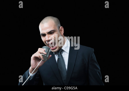 Businessman shouting on a tin can phone Stock Photo