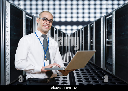 Technician working on a laptop in a server room Stock Photo