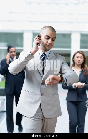 Businessman talking on a mobile phone and checking the time Stock Photo