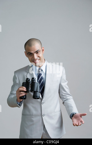 Portrait of a businessman holding binoculars and smiling Stock Photo