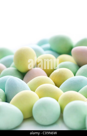 High key vertical of small pastel colored Easter egg candy fading in the far white background. Stock Photo