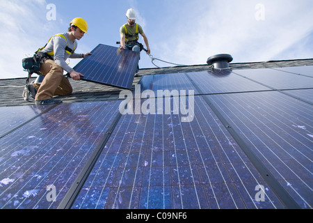 Two workers install solar panels on a rooftop in Redmond, WA. Stock Photo