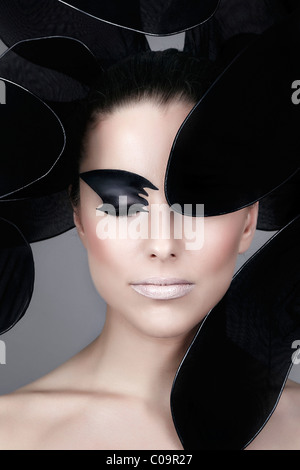 Young woman with elaborate make-up, framed in black stylized flower petals, portrait Stock Photo
