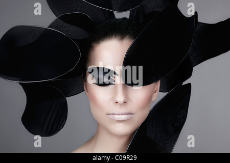 Young woman with elaborate make-up, framed in black stylized flower petals, portrait Stock Photo