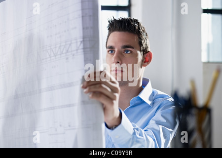 adult caucasian male architect examining blueprints. Horizontal shape, head and shoulders, side view Stock Photo