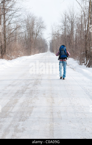 Hitchhiker man walking on an empty road in the wilderness Stock Photo
