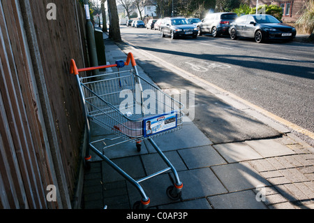 An abandoned supermarket trolley in a suburban residential street in south London Stock Photo