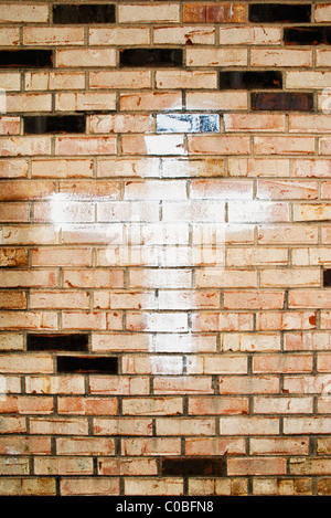 A cross, painted on the back wall of a motel faces an adjacent parking lot. Stock Photo