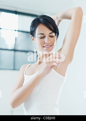 woman putting on stick deodorant and smiling. Stock Photo